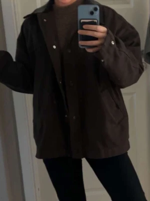 Brun oversized jacka med knappar - Säljer en brun oversized jacka med knappar framtill och stora fickor på sidorna. Jackan har lång ärm och en enkel, stilren design som passar till många olika outfits.