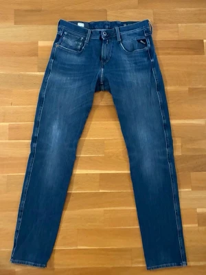 Blå slim fit replay jeans - Snygga blå slim fit jeans med lätt slitna detaljer och klassisk femficksmodell. Jeansen har normalhög midja och smala ben. Materialet är denim med stretch. Modellen heter hyper flex. Perfekta för en avslappnad och trendig look. Storleken är W30 L32 anbass