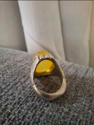 silverring 925 med en gul jemenitisk agatsten - Snygg silverfärgad ring med en stor oval gul sten i centrum. Ringen har detaljerade sidor och en blank finish som ger ett unikt och iögonfallande intryck. Perfekt för dig som vill sticka ut med dina accessoarer.