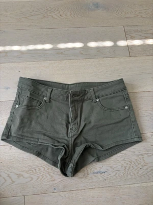 Olivgröna midwaist shorts - Snygga olivgröna shorts med fem fickor och bälteshällor. Klassisk jeansmodell med knapp och dragkedja framtill. Dom är low rise i storlek S vet ej vart dom e från möjligtvis hm! 