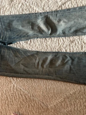 Blå bootcut jeans med vintage-look - Säljer ett par blå bootcut jeans med lätt slitning och vintage-känsla. Jeansen har klassiska bakfickor och en snygg etikett bak i midjan. Jeansen har några defekter exempelvis slitet längst ner på jeansen (se sista bilden), man absolut inget man tänker på!💓💓
