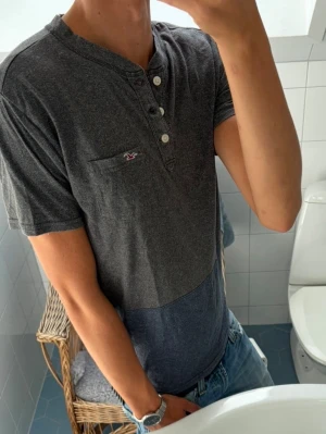Hollister Henley T-Shirt ~ Vintage - Vintage Hollister Henley T-Shirt | Storlek: M | Passform: Normal Fit | Färg: Grå/Blå | Sällsynt 2000s modell | Skick: 9/10 Inga Defekter | Pris ej hugget i sten! 🏄‍♂️ ☀️