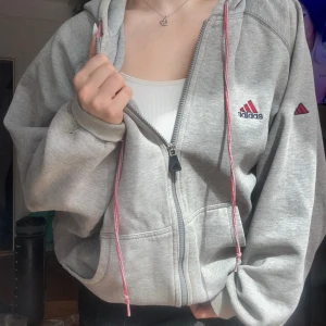 Adidas jacket  - Adidas hettejakke i grått med røde snorer.  Løs og myk, jeg er 155cm og den gir en baggy look. Kan leveres eller hentes i Frogner 