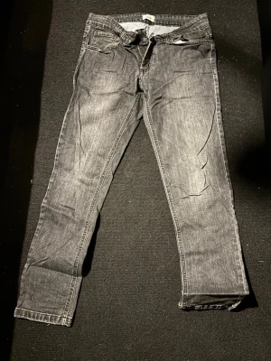 Grå slim fit jeans med tvättad look - Säljer ett par grå slim fit jeans med snygg tvättad effekt och klassiska fem fickor. Jeansen har normal midja och raka ben. Materialet är denim med en mjuk känsla och de har detaljerade sömmar. Perfekta för en avslappnad och trendig stil.