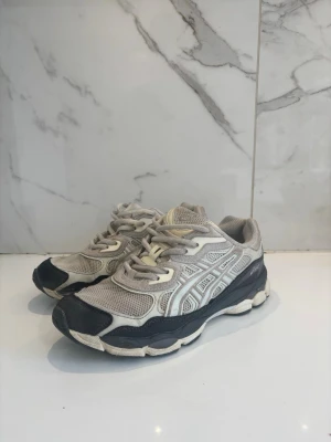 Asics gel skor - Snygga sneakers i grått och svart med vita detaljer och meshpaneler för extra ventilation. Skorna har en chunky sula och klassisk snörning. Perfekta för dig som gillar sportig stil och bekväma skor till vardags.