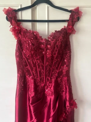 Vinröd balklänning med spets och slits - Säljer min älskade vinröda balklänning❤️ Det är en långklänning från Glamlora med offshoulder-band, spetsdetaljer och blommiga applikationer. Klänningen har en snygg slits framtill och är dekorerad med paljetter på överdelen. Perfekt för bal eller andra festliga tillfällen. Priset kan diskuteras och skriv privat för fler bilder eller andra funderingar!❤️