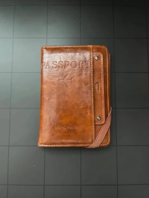 Brunt passfodral / travel wallet med kortfack ✈️ - Praktiskt brunt passfodral och travel wallet – perfekt för resor ✈️🤎  Har plats för pass, kort och andra viktiga resehandlingar. Flera kortfack samt transparent fack på insidan. Elastiskt band håller fodralet stängt.  Storlek ca 15 × 11 cm, se bild med mått.  Kolla gärna mina andra annonser – köp flera saker tillsammans och spara på frakten 🛍️