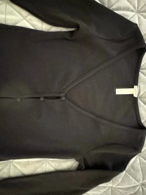 Svart v-ringad crop topp med knappar H&M - Snygg svart crop topp med v-ringning och dekorativa knappar framtill. Långärmad modell i mjukt material som sitter skönt på kroppen. Perfekt att styla med jeans eller kjol för en trendig look.