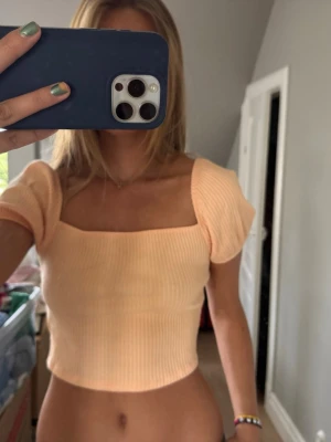 Ljusorange ribbad croppad topp - Trendig ljusorange croppad topp med ribbad struktur och fyrkantig urringning. Toppen har korta puffärmar och sitter tight för en snygg siluett. Köpte för några år sedan på H&M💕💕💕