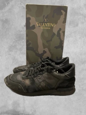 Valentino Garavani skor - Säljer ett par stilrena Valentino Rockrunners i mycket helt okej skick. Lyxiga sneakers i hög kvalitet med de klassiska Rockstud-detaljerna och kamouflage. Allt är såklart äkta.. Hör av dig vid intresse. Pris sänks vid snabb affär!