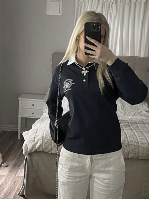 Mörkblå henley med vit krage - Snygg mörkblå henley med vit krage och tryckdetalj på bröstet. Skjortan har lång ärm och knappar framtill. Perfekt för dig som gillar en klassisk men trendig heritage look