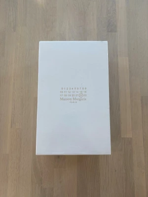 Maison Margiela svarta sneakers - Säljer ett par navy blue Maison Margiela sneakers med klassisk design och gummisula. Skorna har en kombination av läder och mocka, samt vita snören som kontrast. Perfekta för dig som gillar stilrena och exklusiva sneakers.