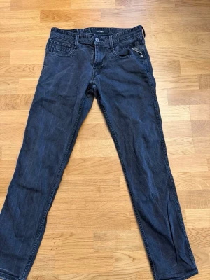 Mörkblå jeans från Replay - Snygga mörkblå jeans från Replay med klassisk femficksmodell och raka ben. Jeansen har silverfärgade detaljer och är tillverkade i ett mjukt denimtyg som sitter skönt. Perfekta för dig som gillar en stilren och tidlös look.