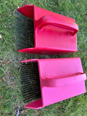 Två röda bärplockare i plast - Säljer två röda bärplockare med handtag och svarta metallpinnar. Perfekta för att plocka blåbär eller lingon i skogen. Tillverkade i tålig plast med ergonomiskt handtag för enkel användning.