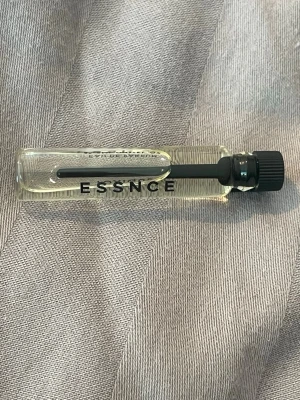 ESSENCE TOXIQUE parfymprov - Liten provflaska med parfymen ESSENCE TOXIQUE. Flaskan är genomskinlig med svart skruvkork och svart text. Innehållet är ljusgult och flaskan har en smal, avlång form. Perfekt att testa en ny doft eller ha med i väskan. Oanvänd.