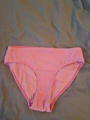 Rosa bikiniunderdel - Säljer ett par rosa bikiniunderdel i mjukt frottéliknande material. Klassisk brief-modell med bredare sidor och resår i midjan. 