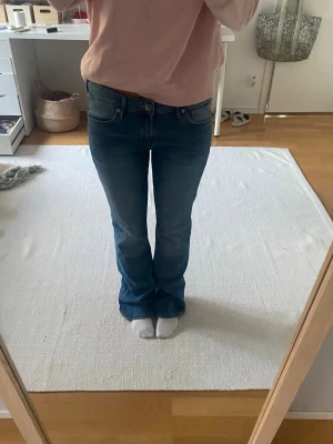 Blå bootcut jeans med låg midja - Säljer ett par klassiska blå bootcut jeans med låg midja och fem fickor. Från by H&M &denim i storlek 31/32. Innerbenslängd: 80 cm. Midjemått tvärsöver: 40 cm💙