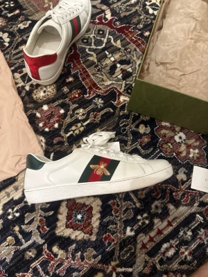 Gucci Ace vita sneakers med bi - Säljer dessa gucci ace som jag köpte på vinted men dom var lite förstora. Dom är storlek 9 vilket motsvarar 43-43,5, väldigt fina i skick. Dom är såklart äkta och nypris ligger på runt 7000kr