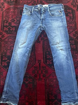 Blå slim fit jeans  - Snygga blå slim fit jeans med lätt slitna detaljer och klassisk femficksdesign. Jeansen har normal midja och raka ben. Materialet är denim i bomull med lite stretch för extra komfort. Perfekta för en avslappnad och trendig look.