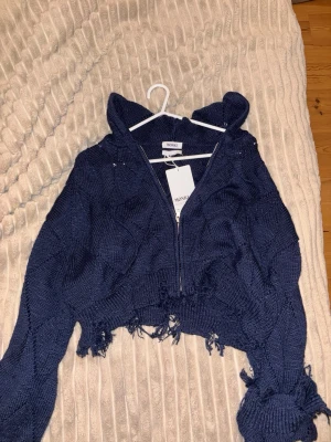 Mörkblå stickad hoodie från MONKI - Trendig mörkblå stickad hoodie från MONKI med dragkedja framtill. Croppad modell med råa, fransiga kanter och luva. Perfekt för en avslappnad och cool stil. Stickad struktur och långa ärmar ger en mysig känsla. fin jacka från weekday/monki, skitsnygg ❤️❤️
