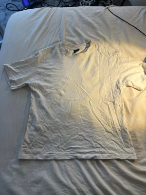 Vit basic t-shirt från Gina Tricot - En enkel och klassisk vit t-shirt från Gina Tricot i storlek XS. T-shirten har rund halsringning och korta ärmar, perfekt att matcha med allt. Tillverkad i mjuk bomull för en skön känsla hela dagen.