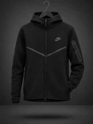 Svart Nike tech - Snygg svart hoodie från Nike med hel dragkedja framtill och huva. Hoodien har två sidofickor med dragkedja och en extra ficka på ärmen. Stilsäker design med diskret Nike-logga på bröstet och V-formad detalj över bröstet. Perfekt för en sportig och avslappnad look.