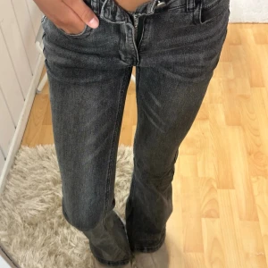 Mörkgrå bootcut jeans - Snygga mörkgrå bootcut jeans med klassisk femficksmodell och hög midja. Jeansen har en lätt tvättad look och raka ben som går ut något nedtill för en trendig siluett. Perfekta till sneakers eller boots för en avslappnad stil.