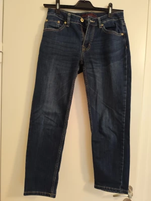 Mörkblå raka jeans med kontrastsömmar - Snygga mörkblå jeans med raka ben och kontrastsömmar. Klassisk femficksmodell med gylf och knappstängning. Jeansen har en tidlös tvätt och passar perfekt till en avslappnad stil. Materialet är denim i bomull.