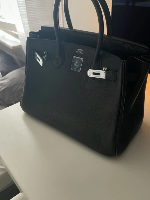 Svart Birkin  - Säljer en svart väska med silver detaljer som har används 