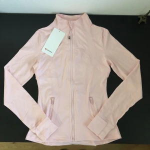 Lululemon Define Jacket Luon – Rosa – Strl 2 - Rosa Lululemon Define Jacket Luon i storlek 2.  Oanvänd. Etiketter sitter kvar. Inga skador eller slitage. Se bilder för skick och detaljer. Skickas snabbt och packas väl. Hör gärna av dig om du har frågor eller vill ha fler bilder.