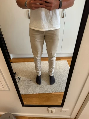  Beige Dondup chinos ”George” - Säljer ett par beige slim fit chinos. Chinosen har en smal passform och är tillverkade i ett mjukt bomullsmaterial med lite stretch för extra komfort. Säljer då mina ben blivit för stora.