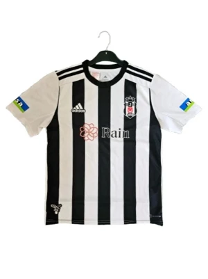 Besiktas matchtröja Adidas - Säljer en svartvit randig matchtröja från Besiktas med Adidas-logga och klubbmärke på bröstet. Tröjan har korta ärmar, rund hals och sponsortryck på bröst och ärmar. Perfekt för fotbollsträning eller att bära på läktaren.