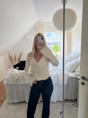 Vit omlottstickad tröja Gina Tricot - Säljer en superfin vit stickad omlott-tröja från Gina Tricot i ullblandning. Tröjan har långa ärmar, v-ringning och knytband i sidan för en snygg passform. Perfekt att styla med jeans eller kjol för en trendig look. Använd 3 ggr