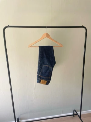 Nudie Jeans 👖  - Nudie Jeans (mörkblå) – Strl W27/L34 👖 Mörkblå jeans från Nudie Jeans med stilren tvätt och klassisk design. Ett mångsidigt par som fungerar till de flesta outfits. I fint begagnat skick. 📏 Storlek: W27/L34 📦 Skick: Bra begagnat skick 💬 Hör gärna av dig vid frågor eller om du vill ha fler bilder!