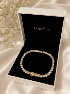     Pandora tennisarmband – Guldfärgat med gnistrande stenar - • Nytt skick • Guldfärgad design med glittrande stenar • Elegant och stilren modell • Levereras utan ask • Ingen stämpel finns