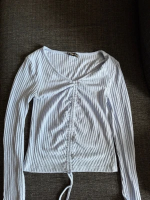 Ljusblå ribbad topp från FB Sister - Supersnygg ljusblå ribbad topp från FB Sister med långa ärmar och snörning framtill. Toppen har v-ringning och croppad passform, perfekt till jeans eller kjol. Materialet är mjukt och stretchigt för en bekväm känsla. Skriv privat för fler bilder eller om du har några frågor💗