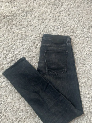 Mörkgrå tapered jeans från Jack & Jones - Snygga mörkblå jeans från Jack & Jones i modellen Tapered/Mike. Klassisk femficksdesign med normal passform och diskreta slitningar. Perfekta till en avslappnad stil och funkar året runt.
