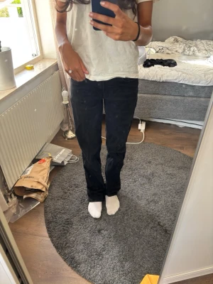 Svarta raka jeans med låg midja - Säljer ett par svarta jeans med rak passform och låg midja från Zara. Jeansen har klassisk femficksdesign och stängs med knapp och dragkedja. Perfekta till en enkel t-shirt eller hoodie för en clean look. Har aldrig använt dessa, de har bara legat i garderoben! 