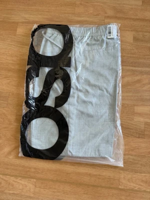 Ljusgrå linnebyxor med resårmidja - Snygga ljusgrå linnebyxor med avslappnad passform och resår i midjan. Byxorna har raka ben och sidofickor, perfekta för en chill och stilren look. Tillverkade i ett lätt och luftigt linnematerial som passar perfekt till varmare dagar.
