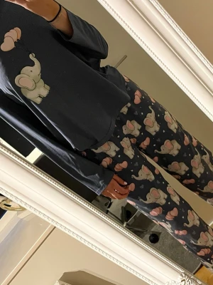 Mörkblå pyjamas sett med elefantmotiv - Supermysig tvådelad pyjamas i mörkblått med söta elefanter och rosa ballonger som tryck. Tröjan har långa ärmar och byxorna är raka och lösa., byxorna har en liten fläck. Vid frågor skriv.💕