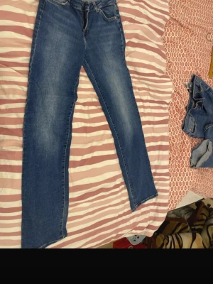 Blå raka jeans med dragkedja - Säljer ett par klassiska blå jeans med rak passform och dragkedja. Jeansen har fem fickor, bälteshällor och snygga slitningar för en avslappnad look. Perfekta till vardags och passar till det mesta i garderoben. I storlek m. Köpta för 699, säljer för 210