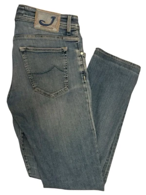 Jacob Cohën blåa jeans - Snygga blåa jeans från Jacob Cohën med klassisk femficksdesign. Det är storlek 34 som passar W30-31 L32 Jeansen har en patch med J-logga bak i midjan och är tillverkade i mjuk denim med lätt tvättad look. Perfekta för en avslappnad stil. Jacob coven märket är speciellt med häst hår vilket är rätt sällsynt nu för tiden 🐎 fina unika knappar. 
