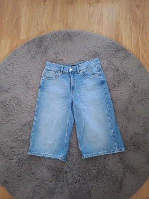 Ljusblå jeansshorts från Lindex - Säljer ett par ljusblå jeansshorts från Lindex i klassisk femficksmodell. Shortsen har normal passform, knapp- och dragkedjestängning samt raka ben som slutar strax under knät. Perfekta för en avslappnad och trendig look.