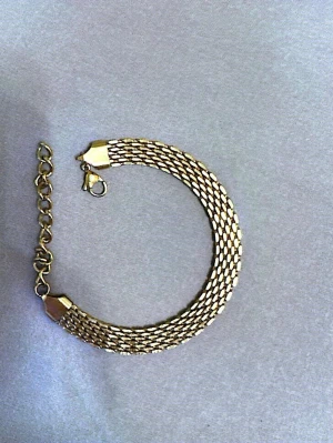 Fint armband i rostfritt stål  - Snyggt armband i guldfärg som passar till allt. Använt men i fint skick. Justerbar storlek så den passar de flesta.  Rostfritt stål Fin guldfärg Lätt att matcha med andra smycken