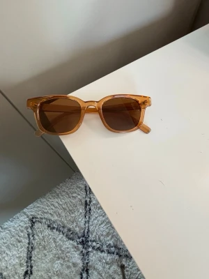  Sthlmstil solglasögon - Snygga solglasögon med transparent brun plastbåge och bruna glas. Modellen har en form som ger en trendig sthlmstilvibe. Perfekta för att lyfta vilken outfit som helst under soliga dagar.