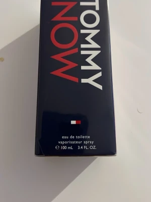 Tommy Now Eau de Toilette 100 ml - Tommy Now Eau de Toilette från Tommy Hilfiger i en snygg marinblå förpackning med röda och vita detaljer. Flaskan rymmer 100 ml och har en klassisk, stilren design med märkets logotyp. Perfekt för dig som gillar fräscha och moderna dofter.