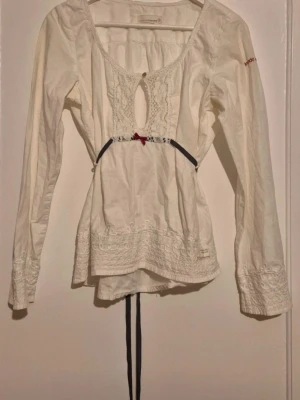 Odd Molly vit blus med spetsdetaljer - Säljer en jättefin vit blus från Odd Molly. Feminin modell med vackra spetsdetaljer framtill, broderier och knytband i midjan. Perfekt till jeans, linnebyxor eller kjol. Fint använt skick. Hör gärna av dig om du vill ha fler bilder eller mått! Lite gulnad på vissa ställen men inget som syns när den är på