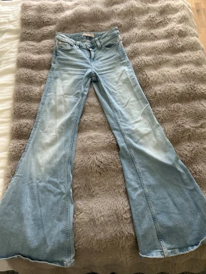 Ljusblå utsvängda jeans Gina Jeans - Säljer ett par ljusblå jeans från Gina Jeans i storlek 34. Jeansen har mid waist och riktigt utsvängda ben för en retro vibe. Klassisk femficksmodell och tillverkade i denim. Perfekta för dig som gillar statement-plagg och vill sticka ut.