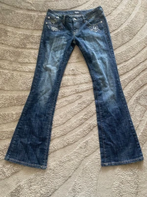 Lågmidjade Bootcut jeans  - Säljer ett par Dolche&Gabbana blå bootcut jeans med snygg brodyr och nitar vid fickorna. Jeansen har låg midja och är tillverkade i 100% bomull. Skulle säga att storleken är XS/S men passar mig som är S. Är villig att gå ner i pris! 