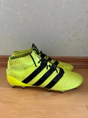 Adidas ACE 16.1 Primeknit FG/AG – Storlek 43 1/3 - Säljer ett par extremt fräscha Adidas ACE 16.1 Primeknit i färgsättningen "Solar Yellow/Core Black" från Speed of Light Pack.  Skorna är testade 2 gånger. Inga skador eller slitage.  En klassisk modell av retroskaraktär som inte längre finns i ordinarie handel.  FG/AG modell som går att använda på konstgräs och naturgräs underlag.  Storlek 43 1/3.